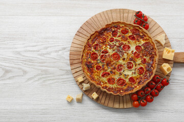 Delicious homemade prosciutto quiche and ingredients on white wooden table, flat lay. Space for text