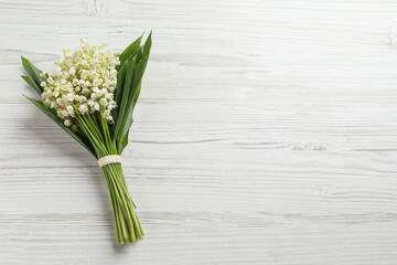Beautiful lily of the valley bouquet on white wooden table, top view. Space for text