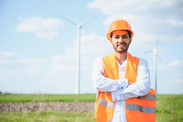 Portrait of focused indian man standing on field with wind turbines