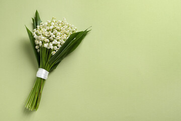 Beautiful lily of the valley bouquet on light green background, top view. Space for text