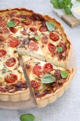 Delicious homemade quiche with prosciutto on light grey table