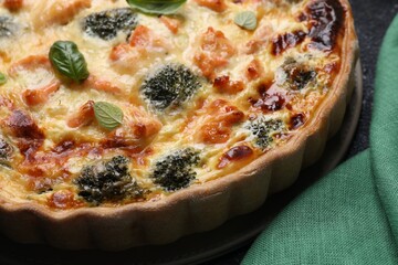 Delicious homemade quiche with salmon and broccoli on table, closeup