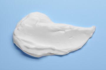 Sample of shaving foam on light blue background, top view