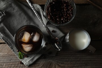 Obraz na płótnie Canvas Delicious iced coffee, mint, milk and beans on wooden table, flat lay
