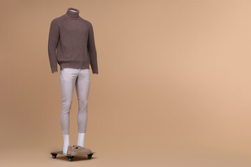 Fototapeta premium Male mannequin dressed in stylish turtleneck and pants on beige background. Space for text