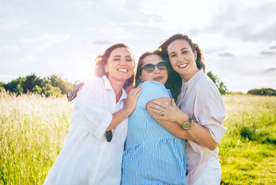 Portrait of three cheerful smiling women embracing during outdoor walking. They looking at the camera. Woman friendship, relations, and happiness concept image.