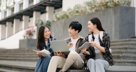 Three young Asian college students and a female student group work at the campus park © Nuttapong punna