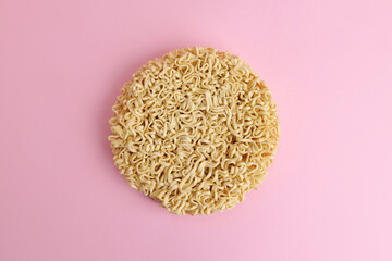 Dry uncooked instant noodles vermicelli on a pink background