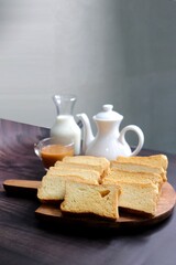 Tea Time Snack. Healthy Wheat rusk served with Indian hot masala tea and milk jug over black background. also known as Mumbai cutting chai. with Copy space. Crunchy rusk or toast.