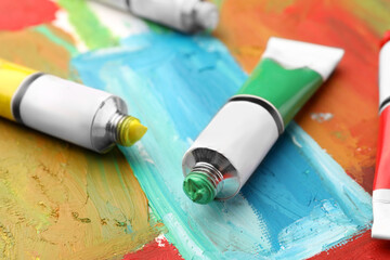 Tubes of colorful oil paints on canvas with abstract painting, closeup