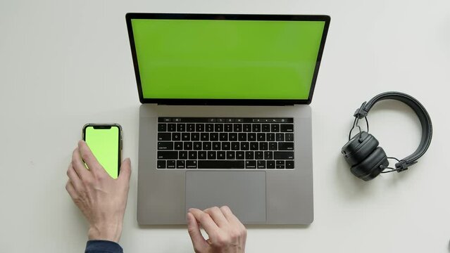 Top View Shot Of Green Screen Laptop, Smartphone And headphones, hdd disc On A Table In The Workspace At Home office . High quality 4k footage