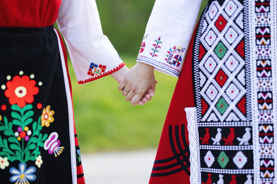 Girls in traditional bulgarian ethnic costumes with folklore embroidery holding hands. The spirit of Bulgaria - culture, history and traditions.
