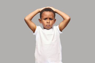 Upset disappointed kid boy in white mockup t-shirt with copy space for your promotional content...