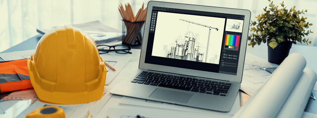 Digital blueprint by architecture design software on laptop screen with documents and blueprint layout on office table seamless integration of technology and traditional drafting method. Insight