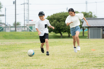 公園でサッカーをするアジア人の子供
