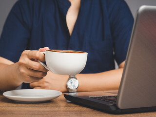 Man in a shirt holding a cup of coffee while sitting at the table.