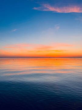 calm orange sea twilights, sky reflection on the city surface, evening seascape background © Oksana