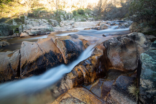 Fotografía de una cascada: Una imagen que muestra una cascada en el río de La Pedriza. El agua cae en cascada desde lo alto de una formación rocosa, creando un hermoso efecto de movimiento