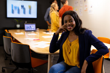 Portrait of happy african american casual businesswoman in meeting room with diverse colleagues