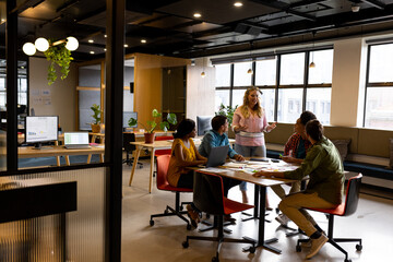 Diverse creative colleagues in discussion brainstorming at table in office