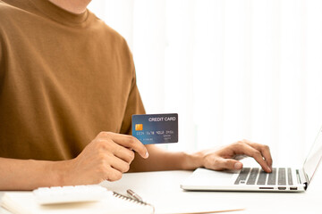 Young man shopping online from the website and uses a credit card to pay for his desired items,...
