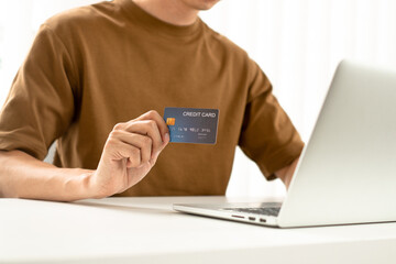 Young man shopping online from the website and uses a credit card to pay for his desired items, ensuring a secure and convenient transaction.