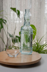 Glass of water with a bottle on table an a brown wooden stand