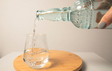 Woman hands holding a bottle of water and pouring water into a glass.close up.