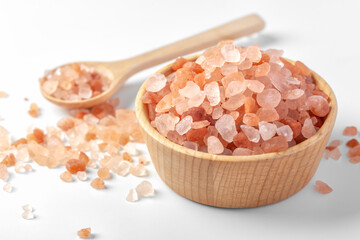 Fototapeta na wymiar Himalayan pink salt in wooden bowl with spoon on white background