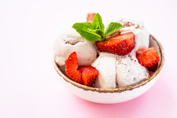 Homemade ice cream with fresh strawberries on pink background. Close up.