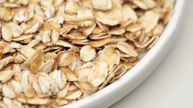 Uncooked oatmeal flakes texture close up. Rotation. Pile of uncooked rolled oats rotating. Oatmeal. Oat flakes. Dry oat flakes grains background. Food background. Gastronomy concept, organic food.