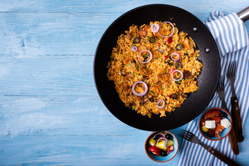Gyros with rice in an iron pan on a blue wooden background.Greek cuisine.Copy space