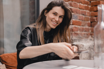 Woman scanning the barcode qr code in restaurant or cafe. Blonde woman use her photo on mobile phone to pay by bills, watching menu or write response. Happy woman like new technology. Easy pay.