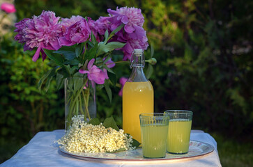 A Bottle and Glasses Of Homemade Lemonade Made From Elderberry Syrup - 612784191