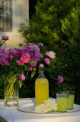 A Bottle and Glasses Of Homemade Lemonade Made From Elderberry Syrup - 612784194
