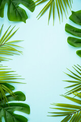 Fototapeta na wymiar Palm leaves on blue background. Flat lay with copy space.