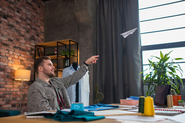 A man throws a paper airplane up high at the ceiling and then gets back to work as he is bopping...