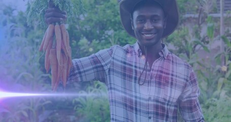 Video of blue lights over smiling african american man holding carrots