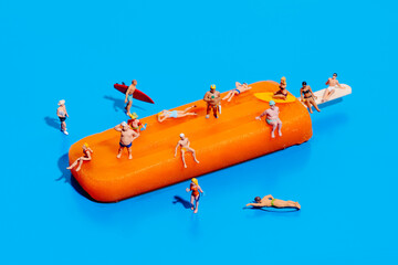 miniature people in swimsuit on an orange popsicle - obrazy, fototapety, plakaty