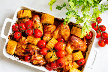 Oven baked chicken wings with homemade tomato or bbq sauce, corn cobs and cherry tomatoes.