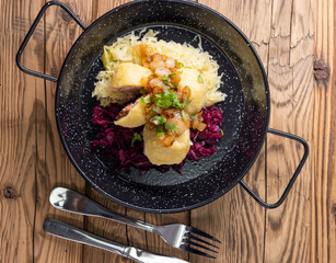 dumpllings filled with smoked meat served with red and white cabbage
