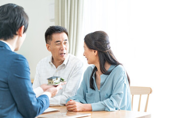 住宅模型を持つ営業マンと日本人夫婦