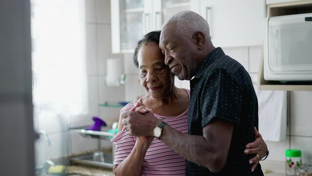 Candid Romantic Moment of Elderly African American Couple Dancing in Home Kitchen