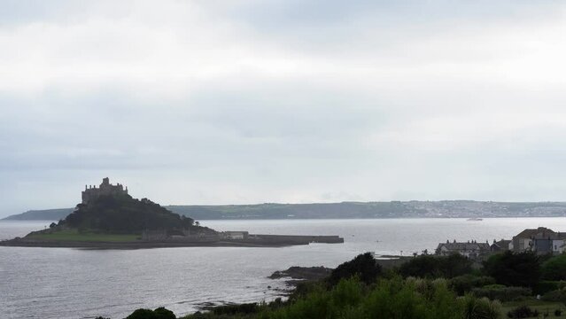 View from a terrace in Marazion of the english medieval castle and church of St Michael's Mount in Cornwall on a cloudy spring day.Zoom in 4k footage
