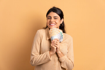 cheerful young woman showing money, brazilian currency in all beige colors. business, loan, pay,...