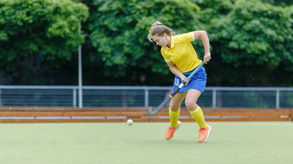 Field hockey female player leading the ball in attack. Young woman playing in field hockey tournament