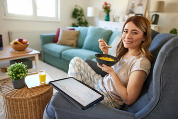 Smiling woman with digital tablet and breakfast at home