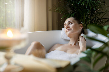 woman enjoying spa bath with foam and wooden massage brush. body care - 612806778