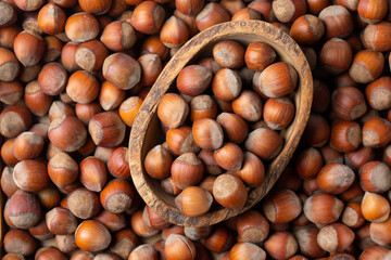 Hazelnuts as background.  Nuts in shell in wooden bowl. Top view.