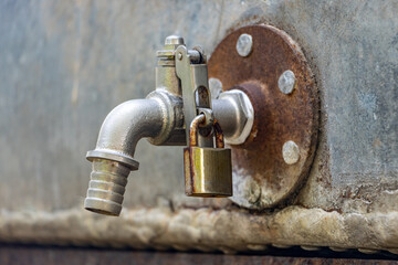 A water tap on the cistern locked with a padlock, close up